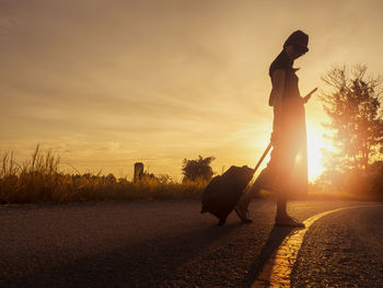 Silhouette person standing on field against sky during sunset