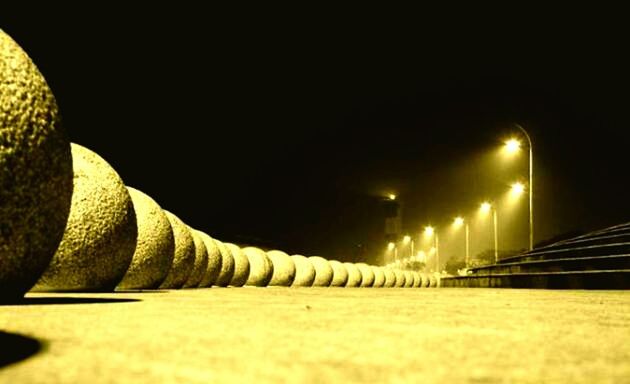 night, illuminated, copy space, clear sky, surface level, lighting equipment, transportation, railing, built structure, dark, architecture, city, road, light - natural phenomenon, street, the way forward, speed, outdoors, blurred motion, street light