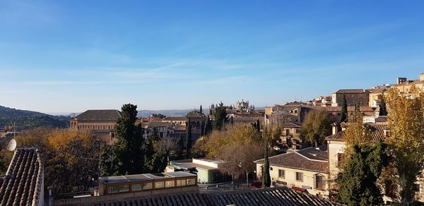 High angle view of buildings in city against blue sky