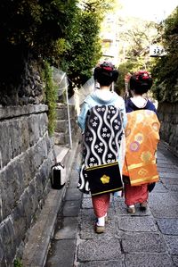 Rear view of women wearing kimono while walking on footpath