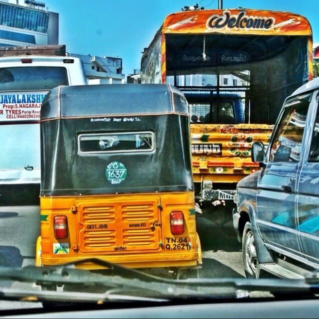 transportation, mode of transport, land vehicle, car, yellow, public transportation, travel, street, text, on the move, building exterior, western script, city, blue, information sign, bus, communication, guidance, road sign, architecture