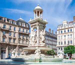 Statue of fountain in city against sky