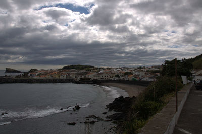 High angle view of town by sea against cloudy sky