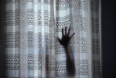 Close-up of human hand against curtain