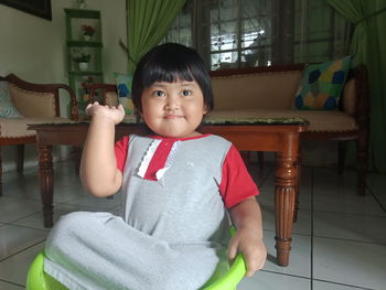 Portrait of cute boy sitting on chair at home