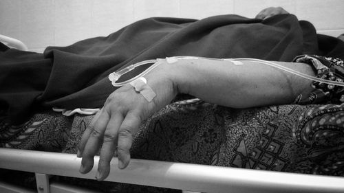 Midsection of woman sleeping on bed in hospital