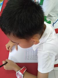 High angle view portrait of boy holding paper on table