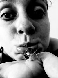 Close-up portrait of woman with snail on finger