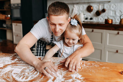 Funny happy dad and daughter baby cook together fool around and play with flour in  kitchen at home