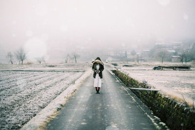 Rear view of man walking on road during winter