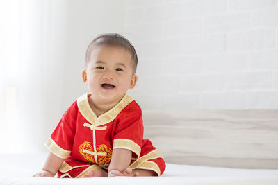 Portrait of cute boy sitting against wall