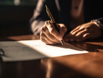 Midsection of man writing in book