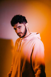 Portrait of young man standing against yellow wall