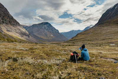 Rear view of men on mountain against sky