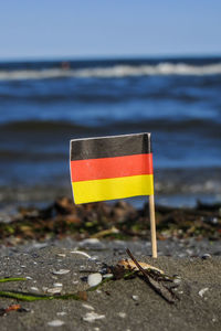 Close-up of flag by sea against sky