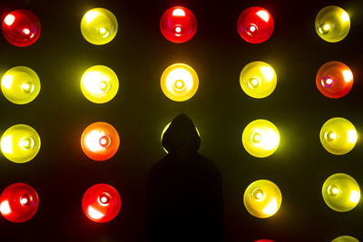 Silhouetted hacker in front of red and yellow illuminated lights