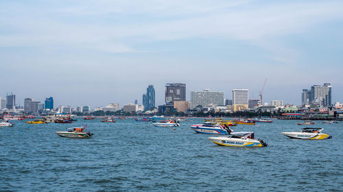 Boats in sea by buildings against sky