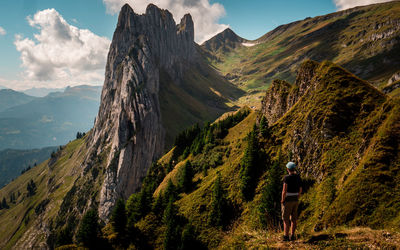 Rear view of man walking on mountains against sky