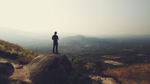 Rear view of man standing on rock formation at mountain