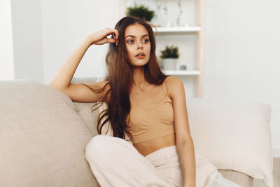 Portrait of young woman sitting on bed at home