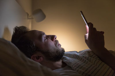 Adult sleepy male lying on his back and surfing in web before dreaming. social media addiction