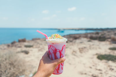 Close-up of hand holding ice cream on beach