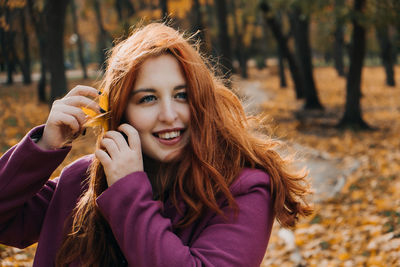 Autumn portrait of candid beautiful red-haired girl with fall leaves in hair.