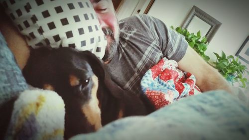 Midsection of man with dog relaxing on bed at home