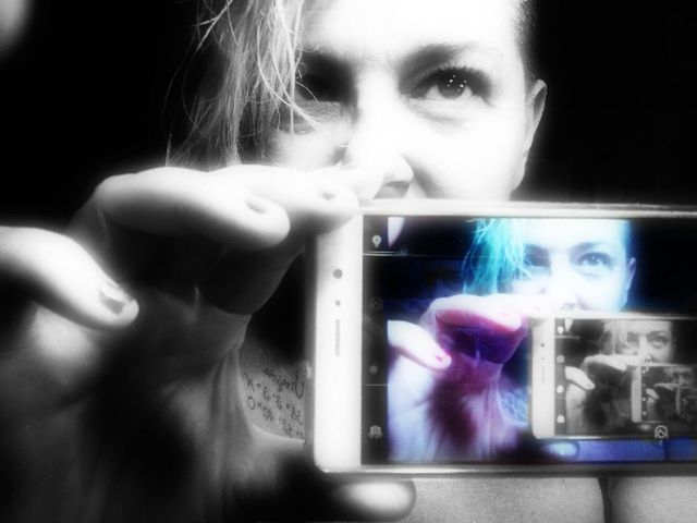 CLOSE-UP OF WOMAN HAND HOLDING CAMERA WHILE STANDING ON STAGE