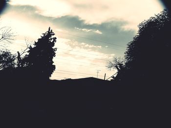 Low angle view of silhouette trees against cloudy sky