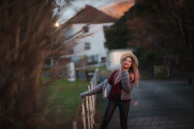 Portrait of smiling young woman standing against trees