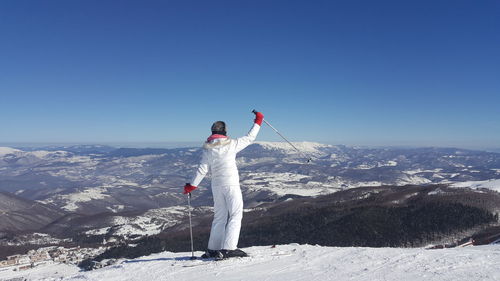 Rear view full length of woman skiing on snowcapped mountain