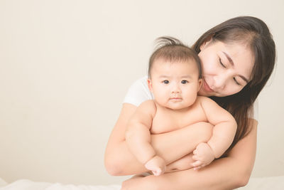 Portrait of cute baby girl sitting against white background