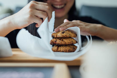 Smiling woman wrapping cookie in paper at home