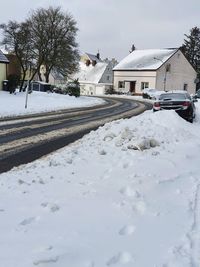 Snow covered houses by buildings in city