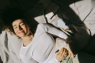 Directly above shot of young woman lying by dog on bed at home