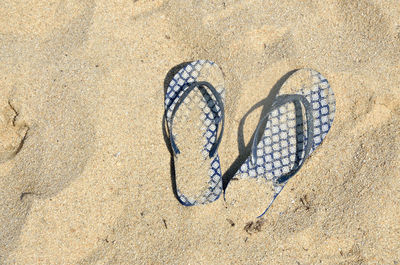 Blue flip flops covered with sand left on beach