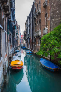 Boats moored in canal amidst buildings