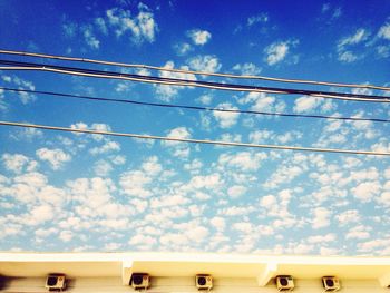 Low angle view of power lines against blue sky