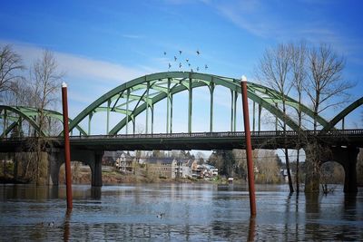 Bridge over river in city against sky