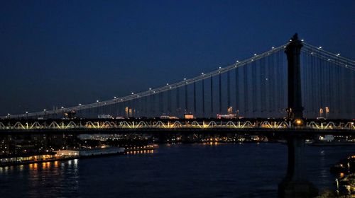 Illuminated bridge over river against sky at night