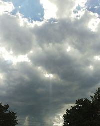 Low angle view of sunlight streaming through clouds