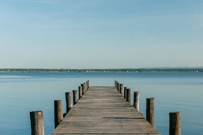 Wooden jetty on pier in sea against clear sky