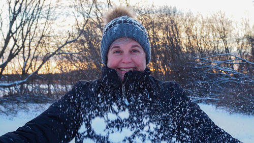 Portrait of woman in snow against trees during winter