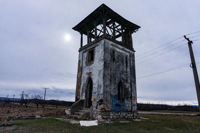 Low angle view of old abandoned house on field against sky