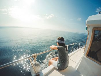 Man sitting on boat in sea against sky