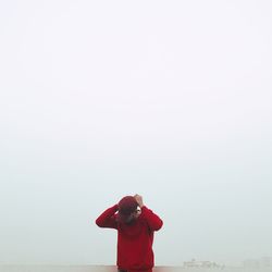 Rear view of woman photographing against clear sky