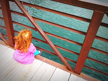 High angle view of girl sitting on pier over sea