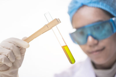 Close-up of female scientist holding chemical in test tube against white background
