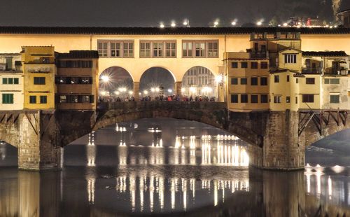 Arch bridge over river in city at night